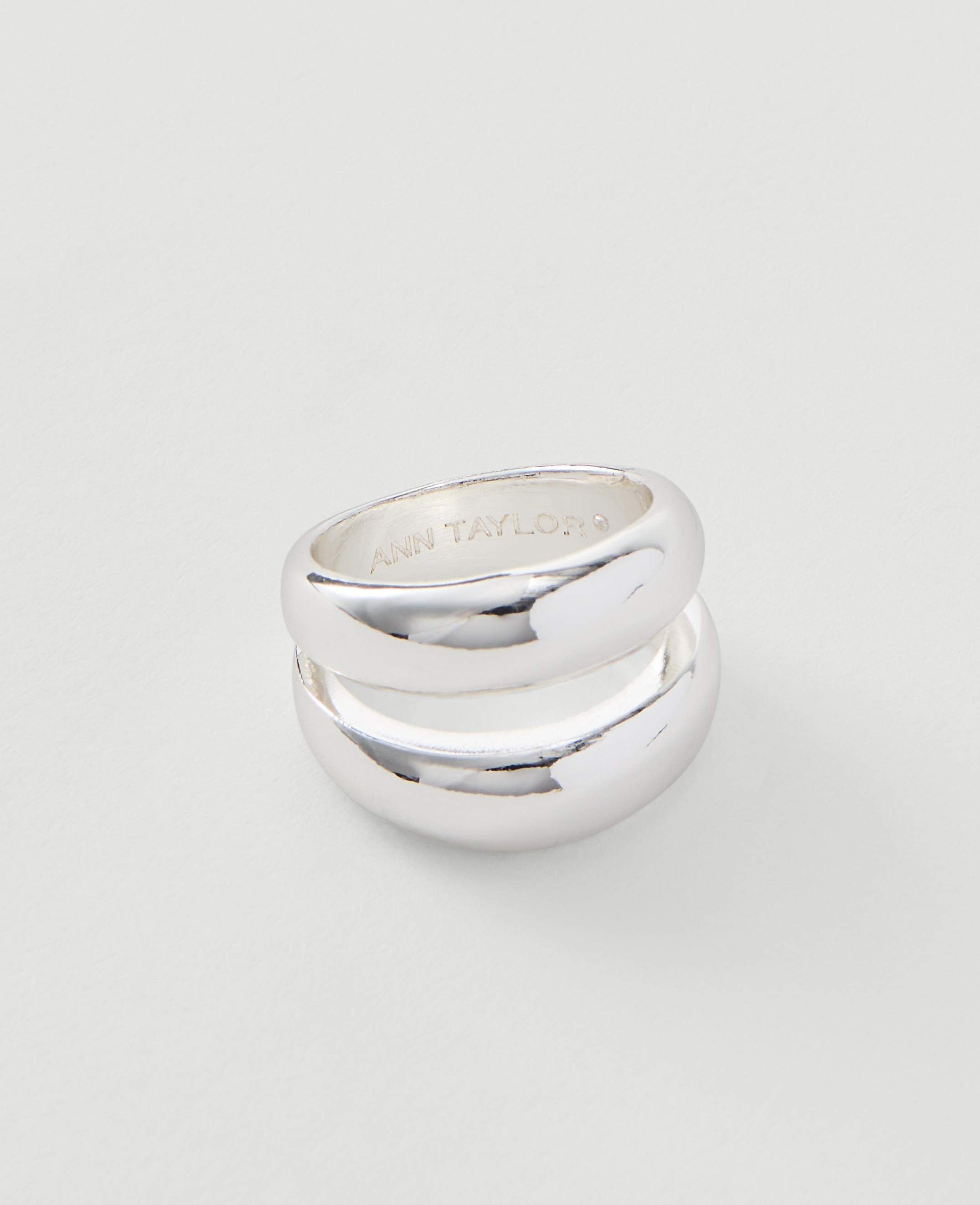 A silver Ann Taylor ring with a smooth, rounded design rests on a plain white background.