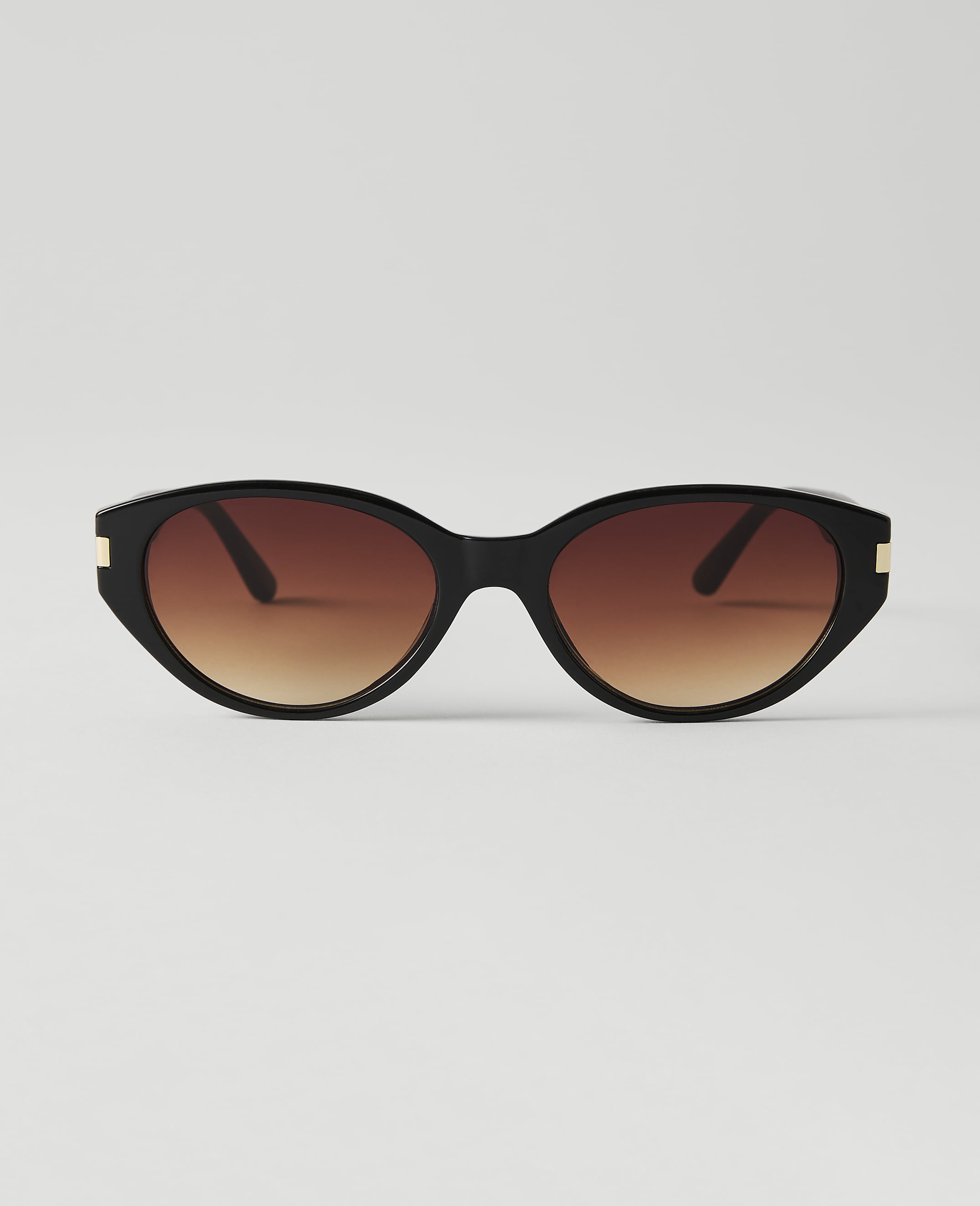 Black cat-eye sunglasses with gradient brown lenses are centered against a plain white background.