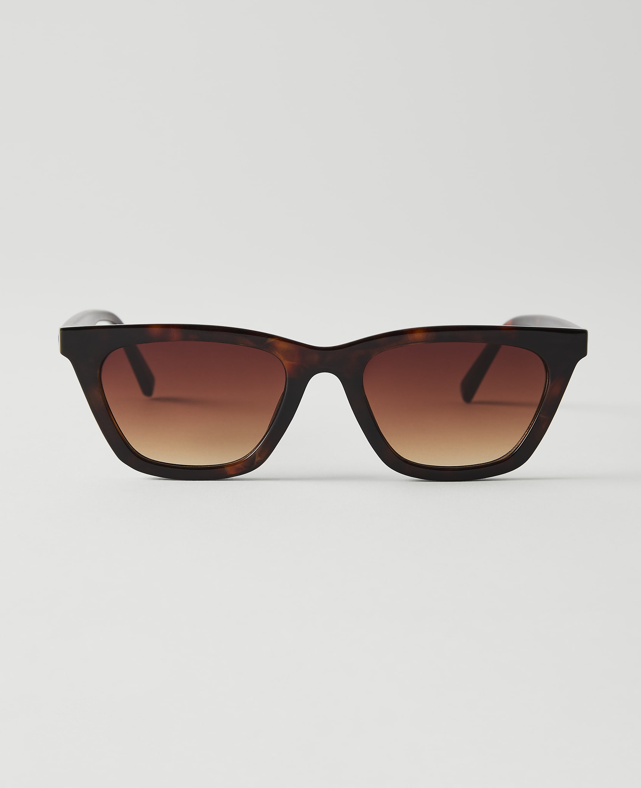 Tortoiseshell sunglasses with gradient brown lenses are centered against a plain white background.