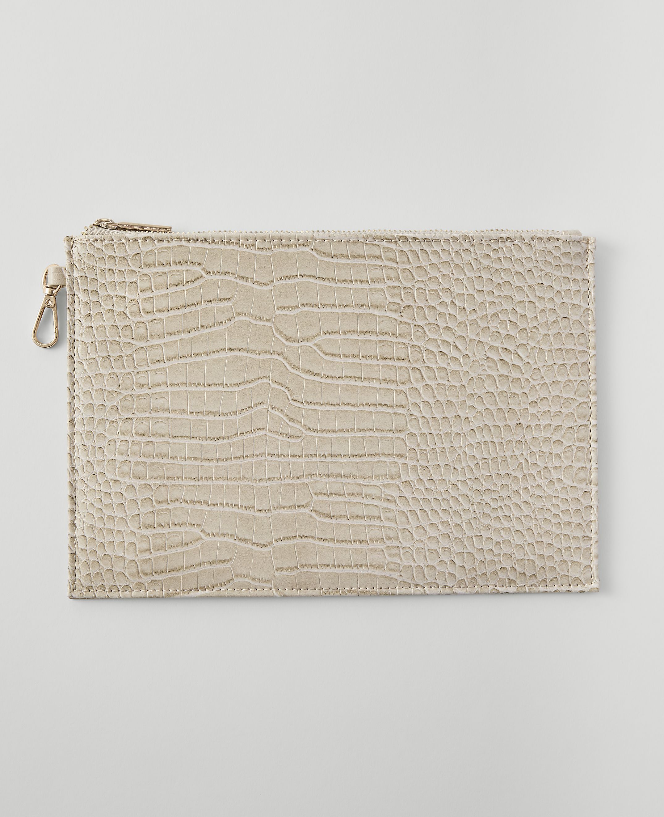 A beige, crocodile-embossed clutch with a gold zipper and clasp rests on a plain, light gray background.