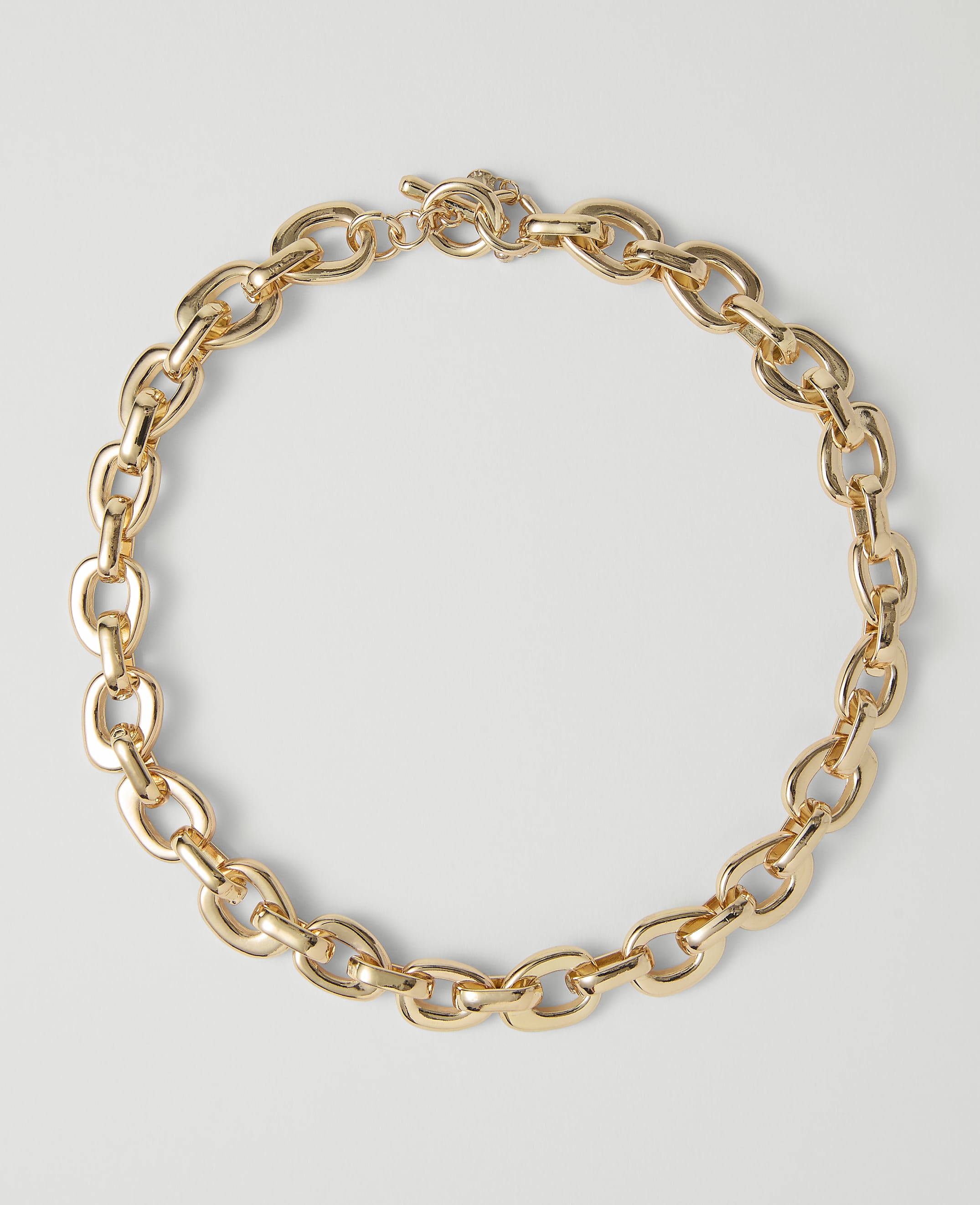 A chunky gold chain necklace with a toggle clasp rests on a plain white background.