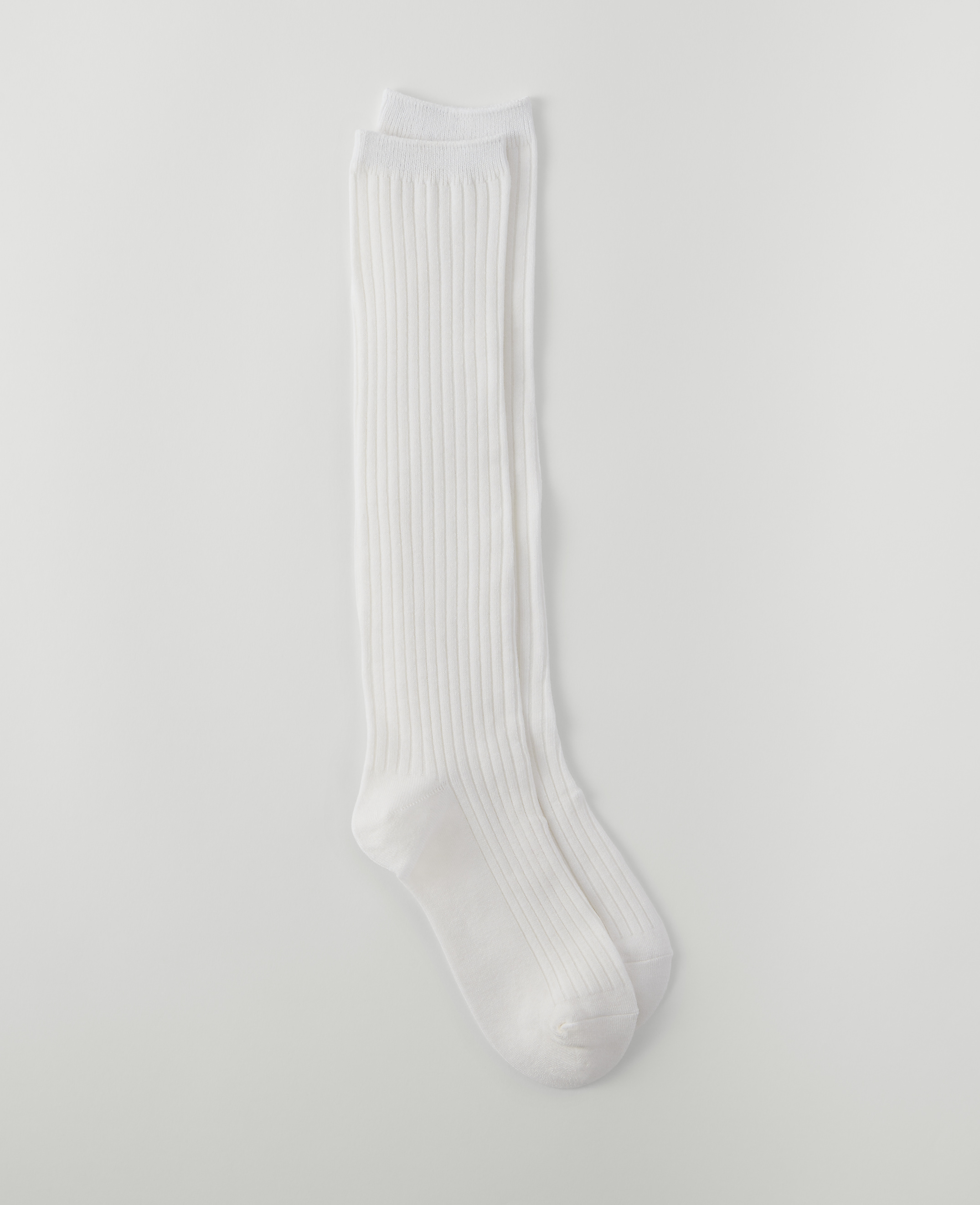 A pair of white ribbed knee-high socks lies on a plain white background.
