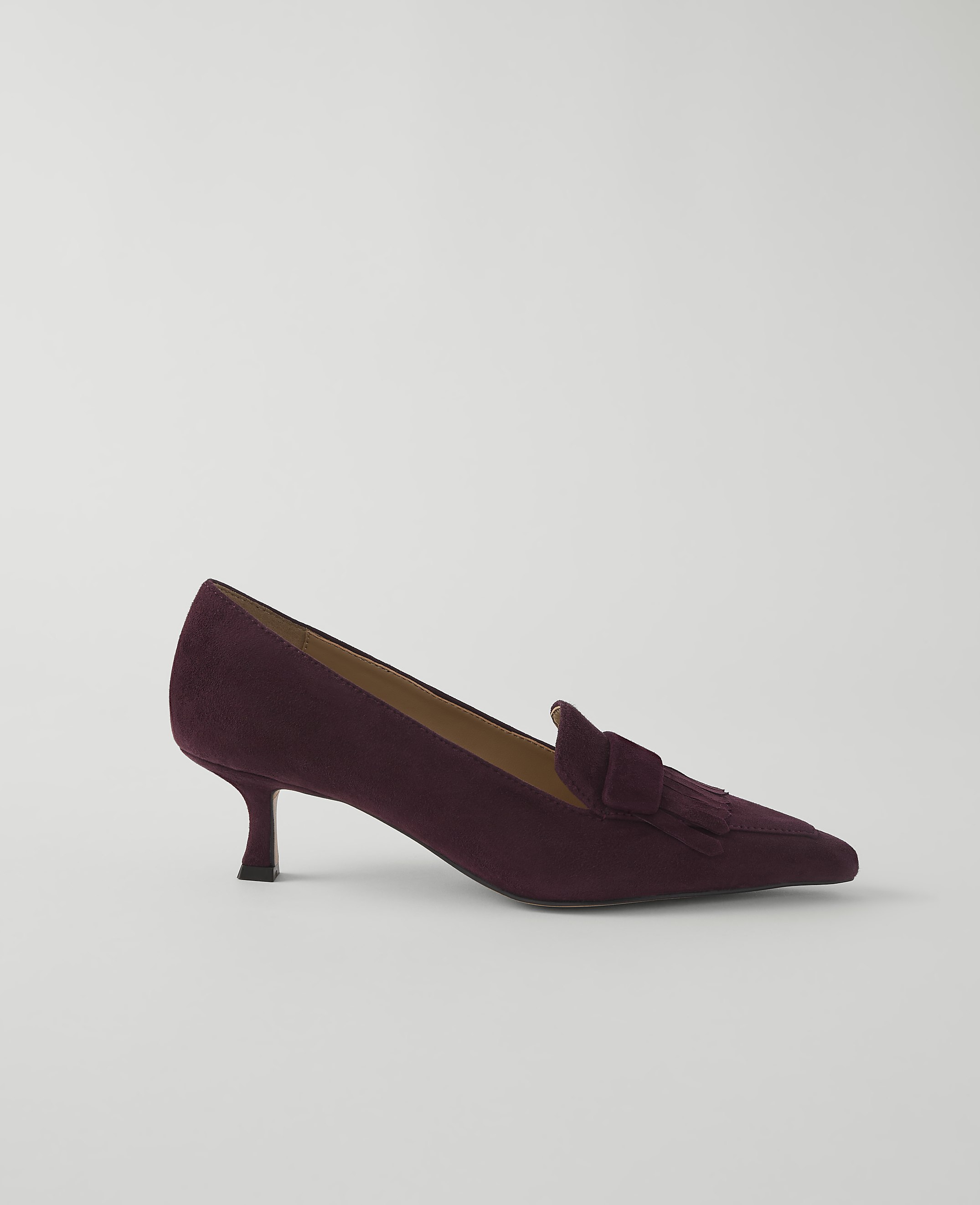 A burgundy suede loafer with a pointed toe and a kitten heel rests on a plain white background.
