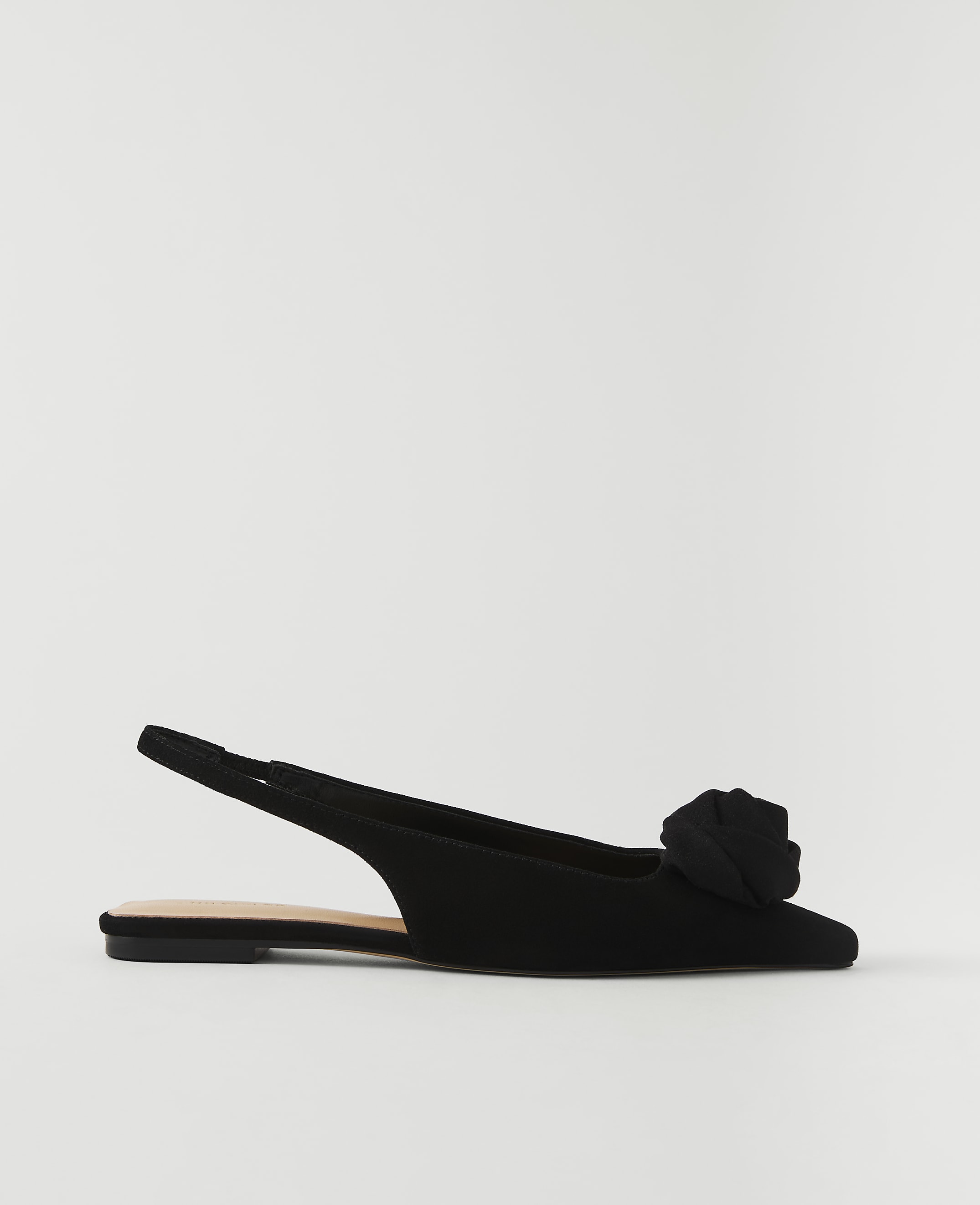 A black slingback flat with a rose embellishment sits against a plain white background.