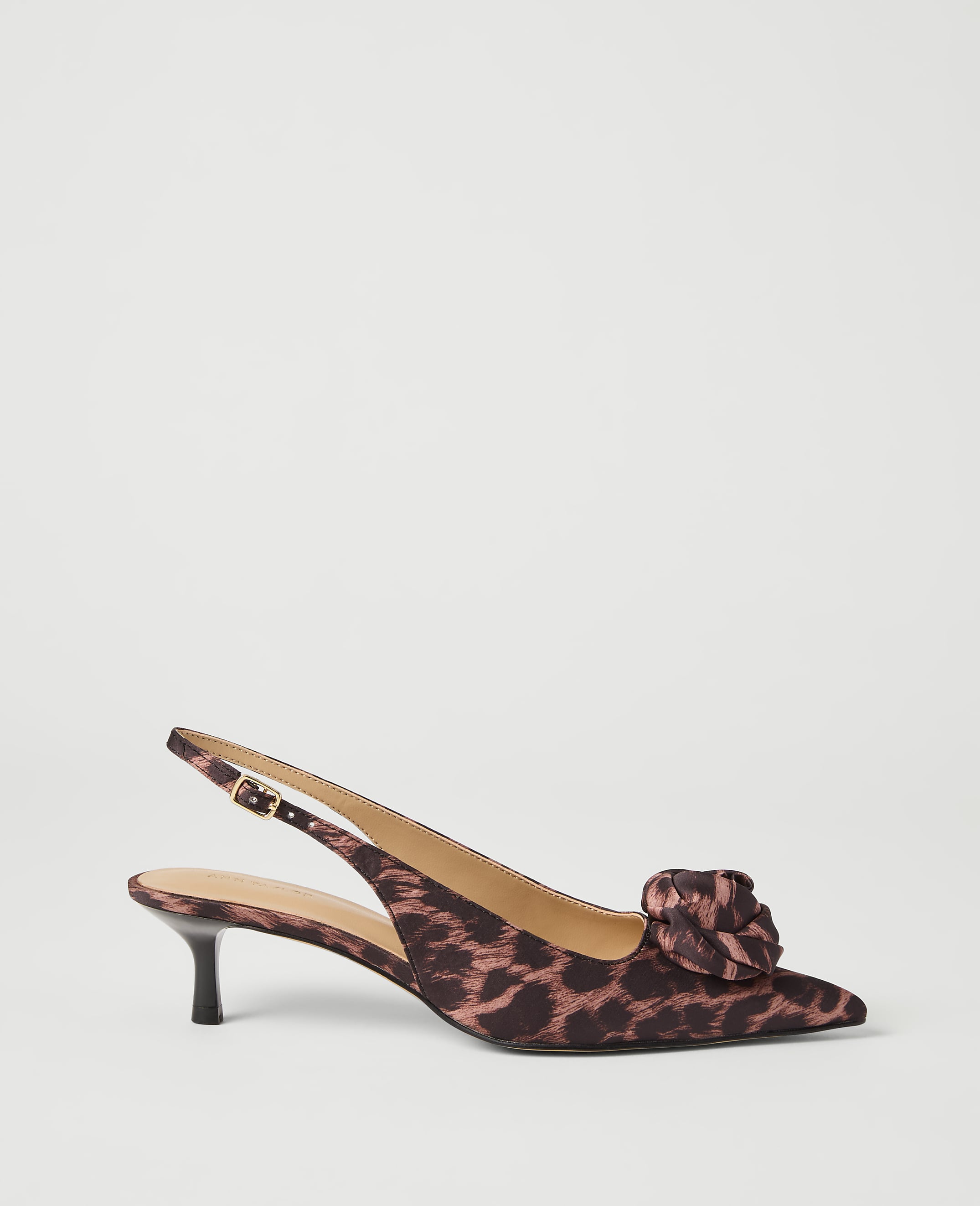 A leopard-print slingback heel with a floral embellishment rests on a plain white background.