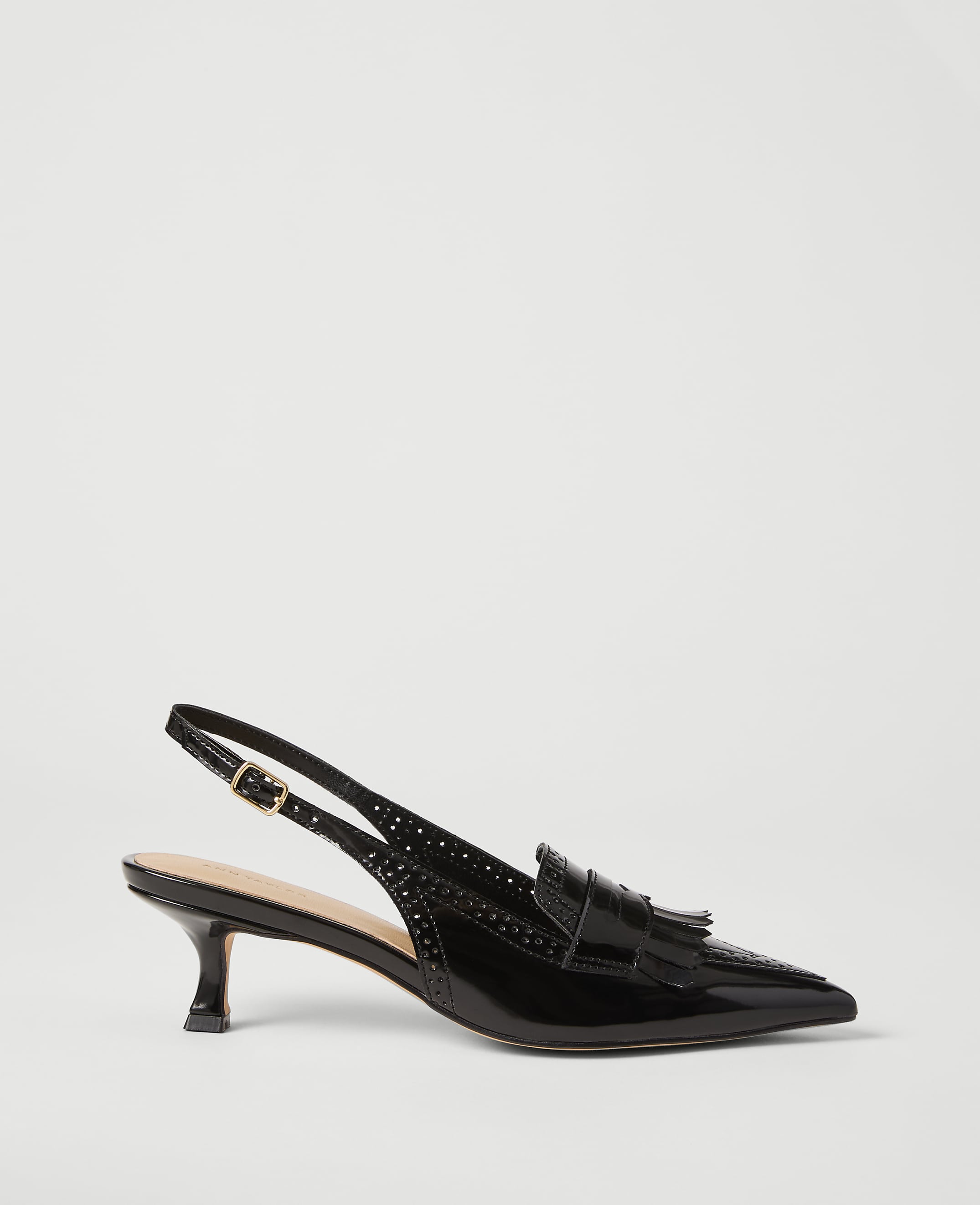 A black patent leather slingback shoe with a tassel detail sits on a plain white background.