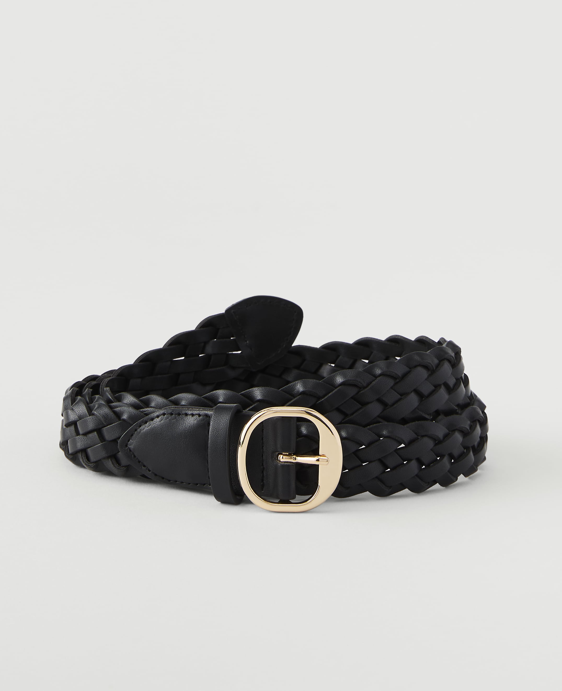 A black braided leather belt with a gold oval buckle lies coiled on a plain white background.