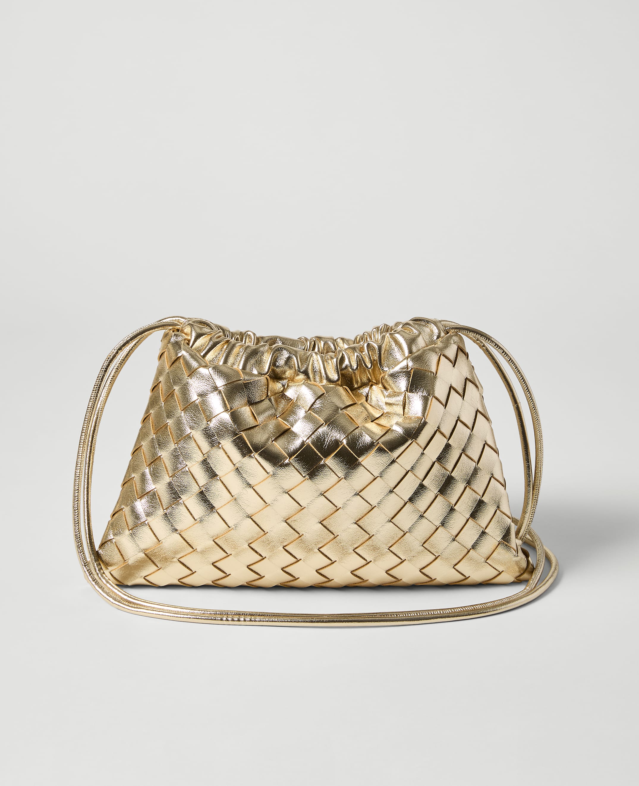 A metallic gold woven drawstring pouch bag rests on a plain light gray background.
