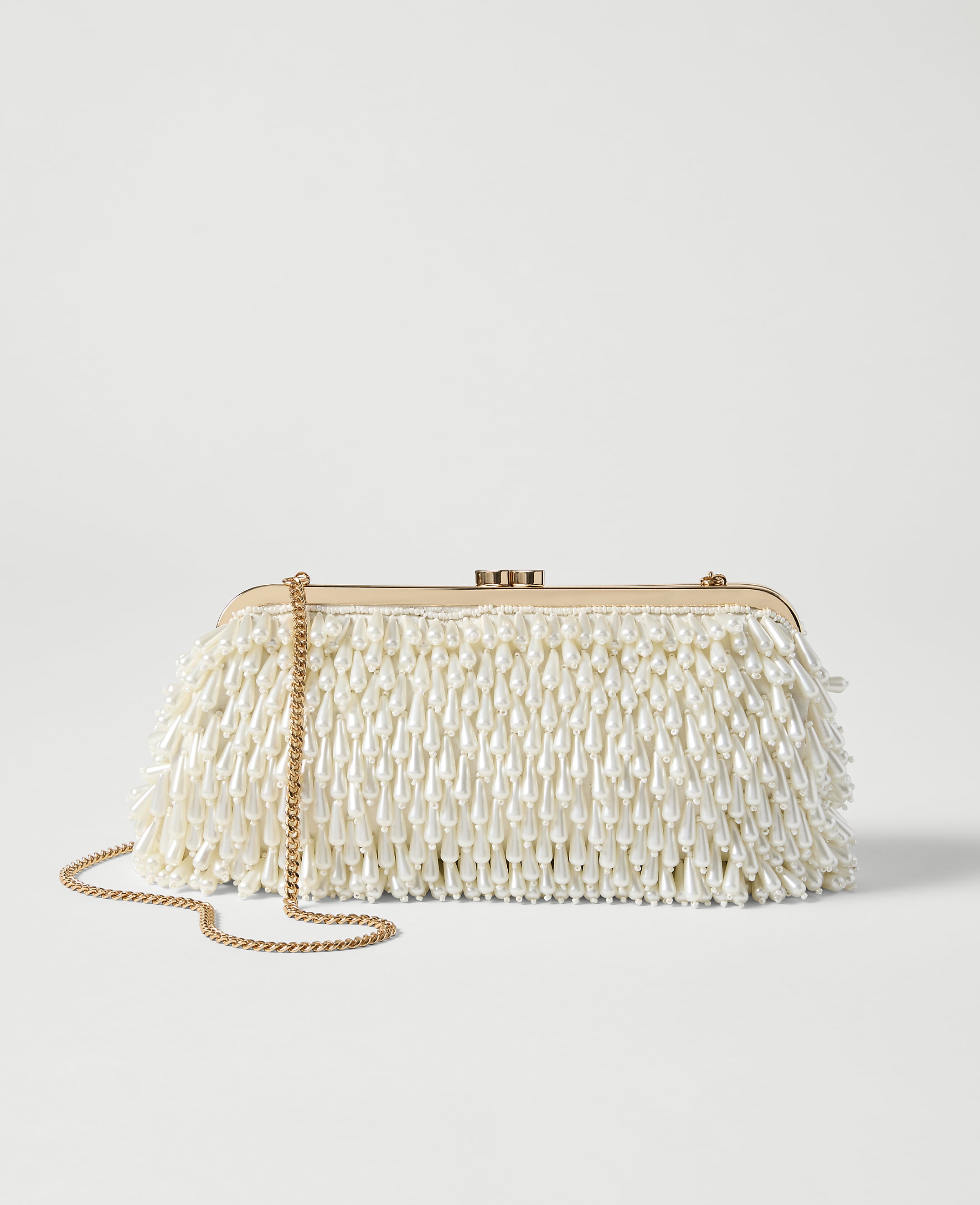 A beaded clutch with a gold chain rests on a plain, light gray background.