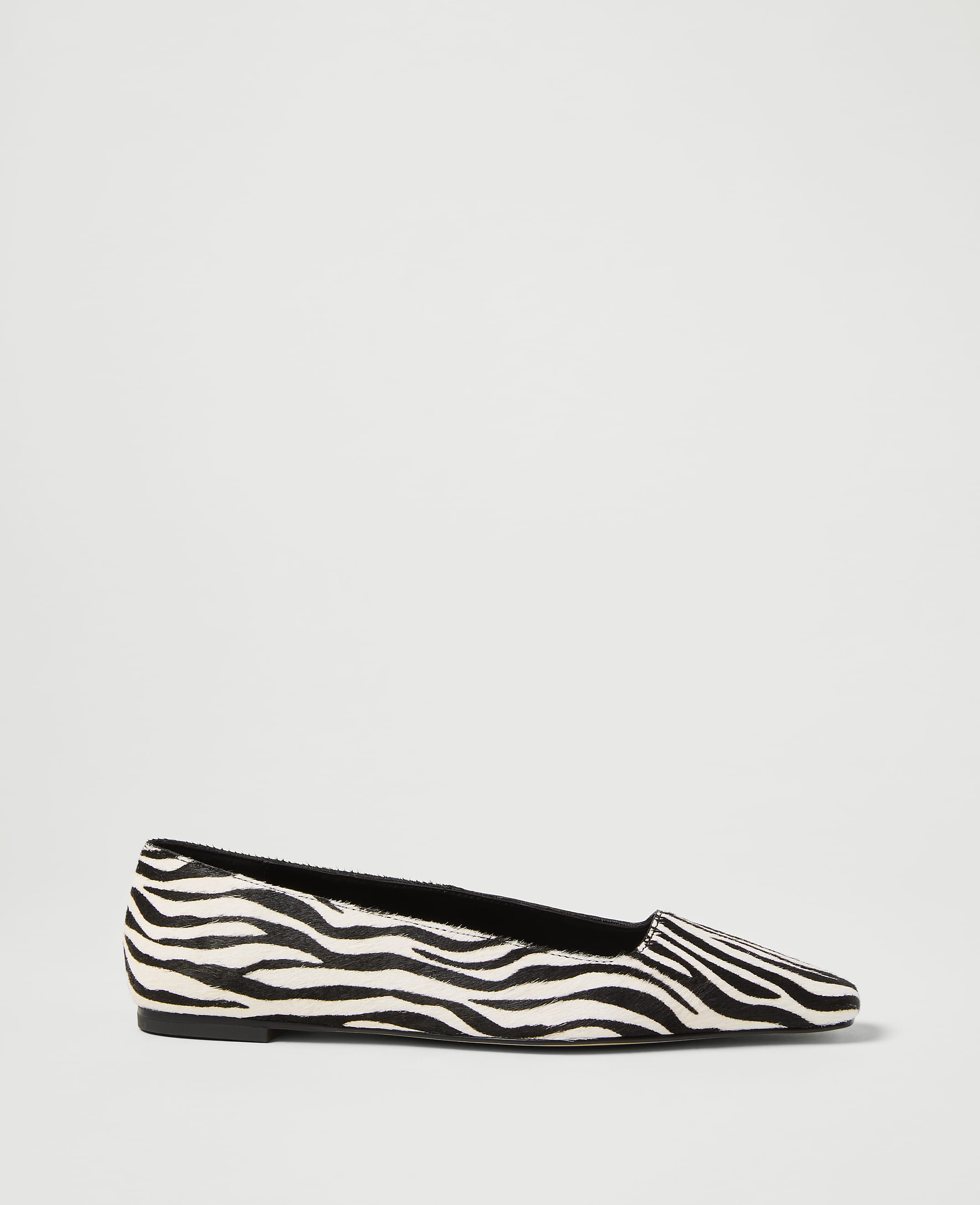 A zebra-print flat shoe rests on a plain white background.