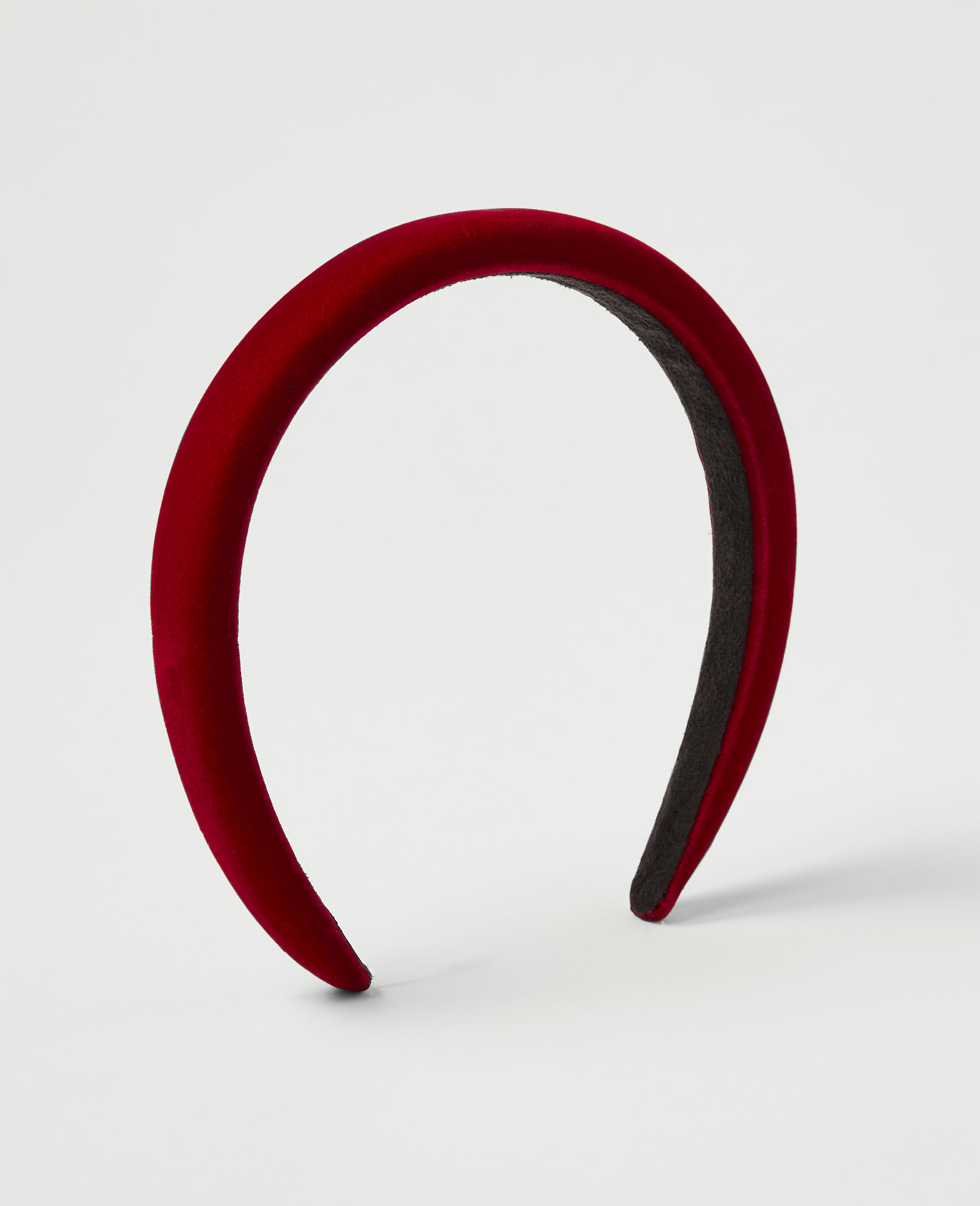 A plush red headband rests on a plain white background.