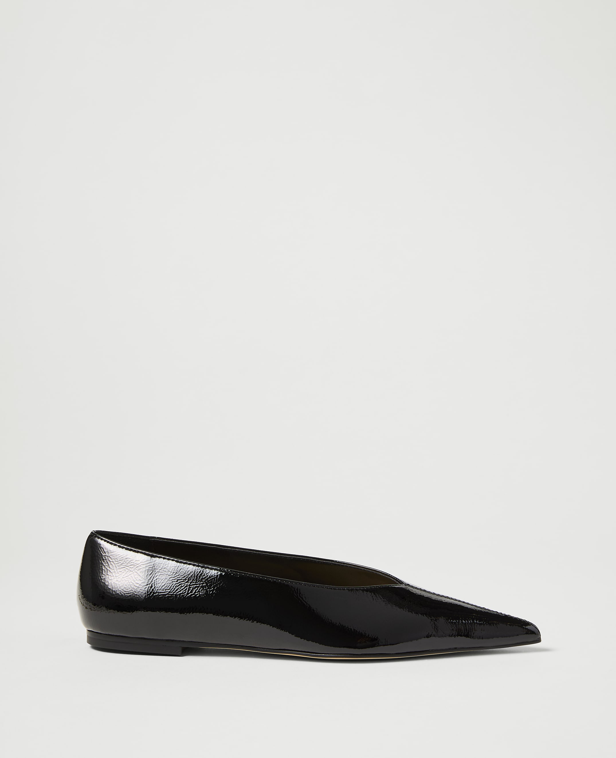 A glossy black pointed-toe flat shoe rests on a plain white background.