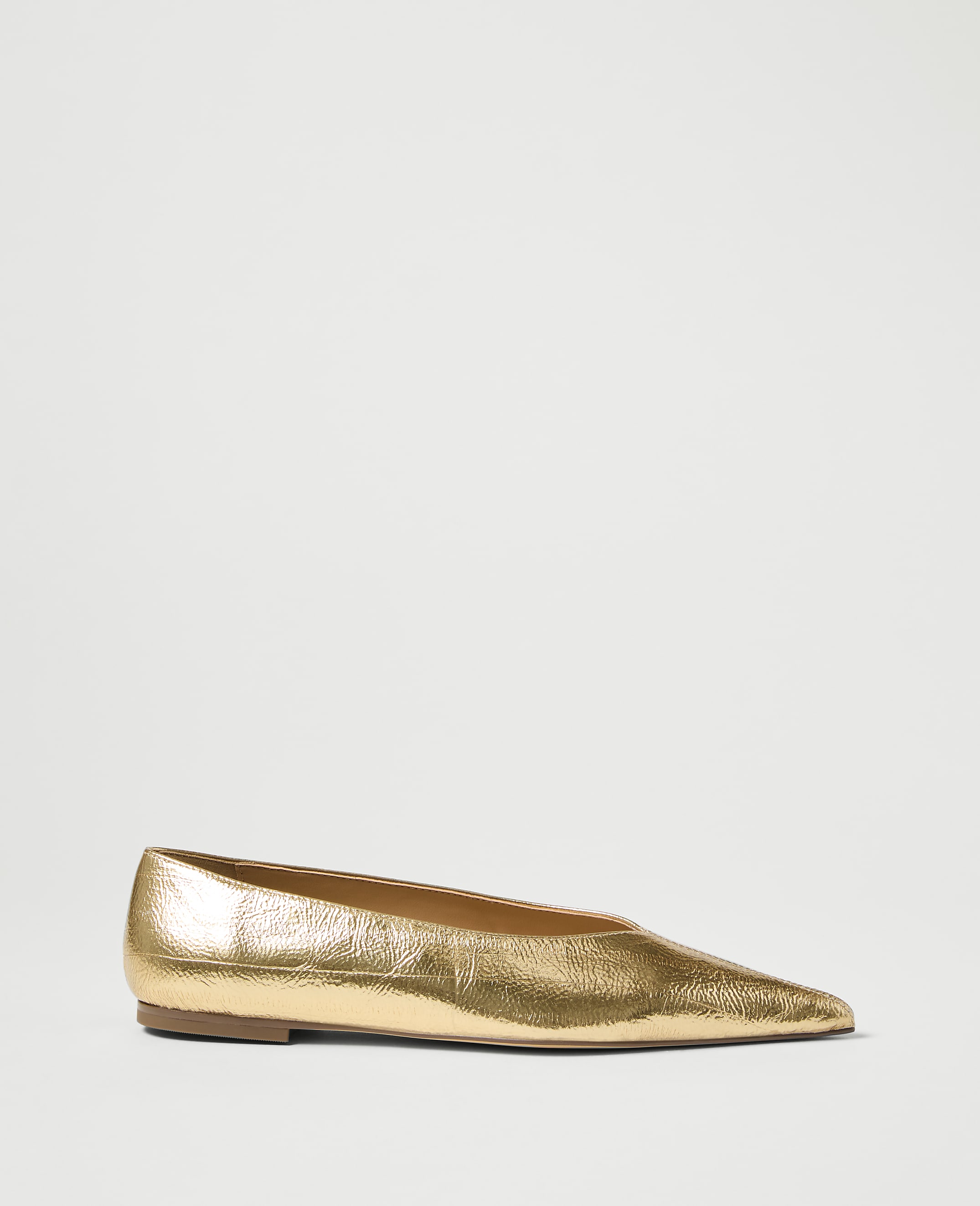 A metallic gold pointed-toe flat shoe rests on a plain white background.