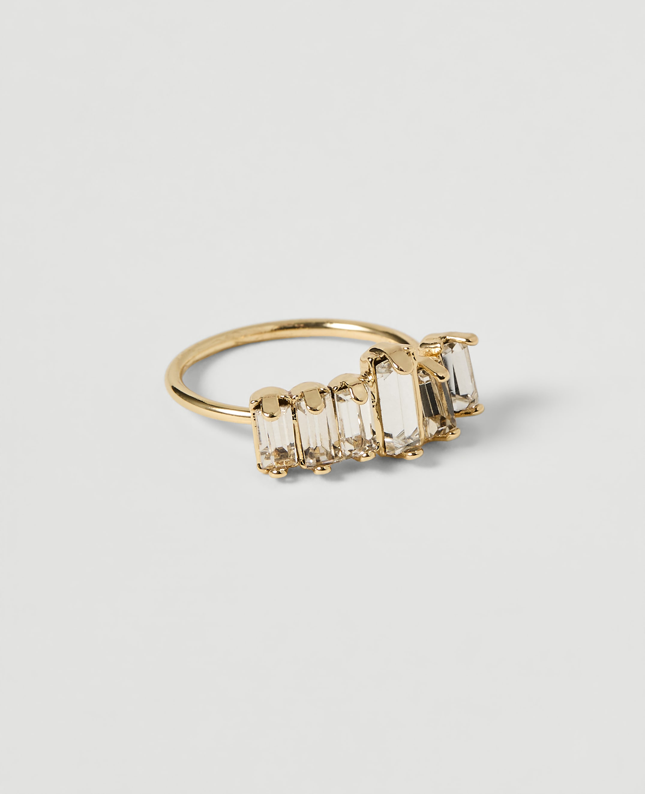 A gold ring with baguette-cut clear stones is displayed on a plain white background.