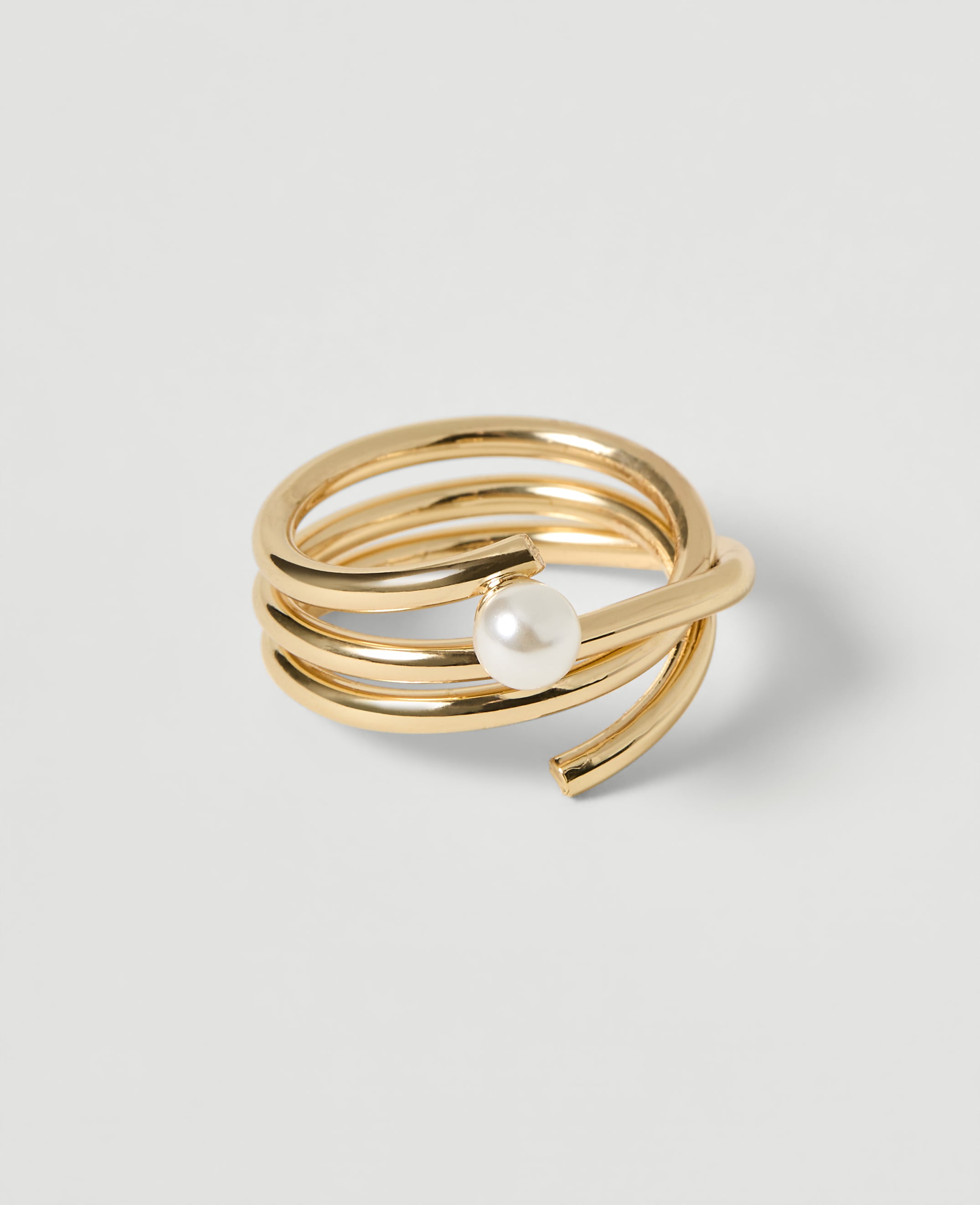 A coiled gold ring with a pearl accent rests on a plain white background.
