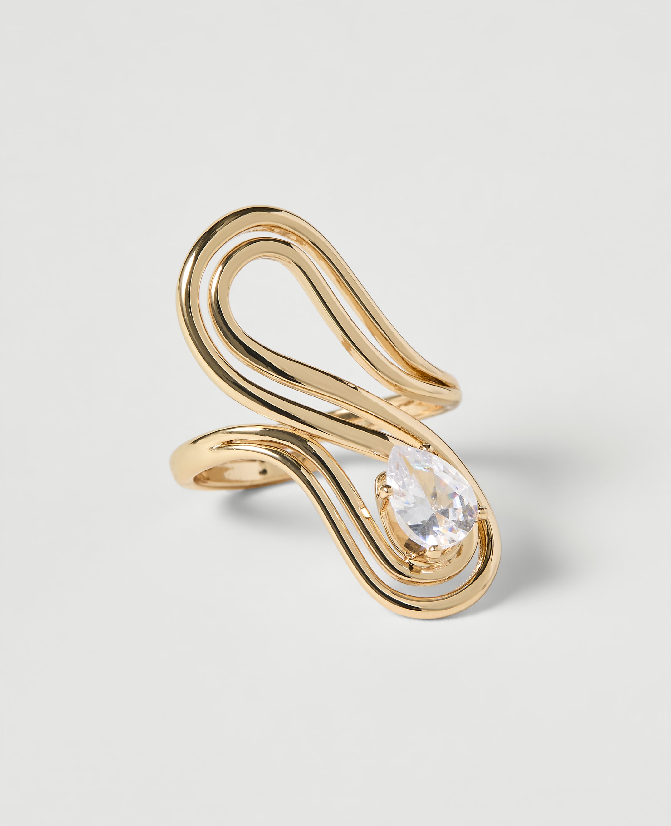 A gold ring with a pear-shaped diamond sits on a plain white background.