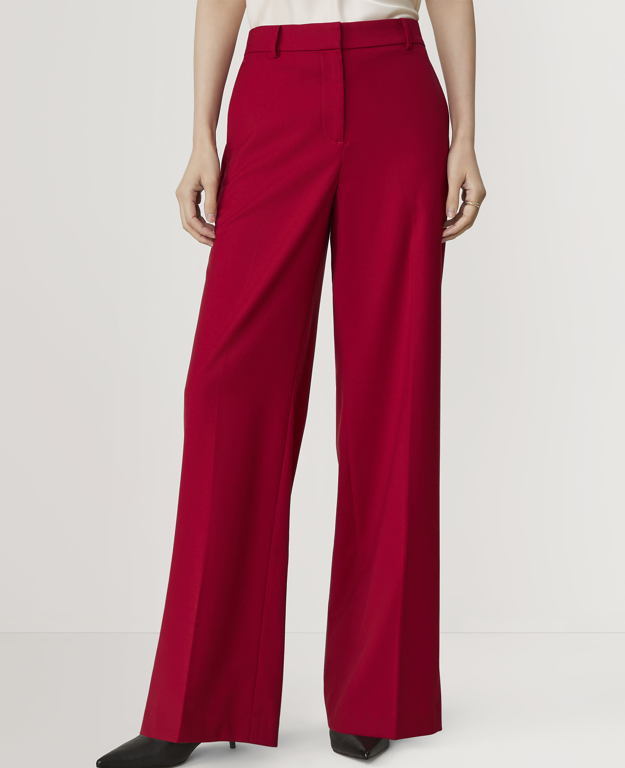 A person in bright red wide-leg trousers stands against a plain white background.