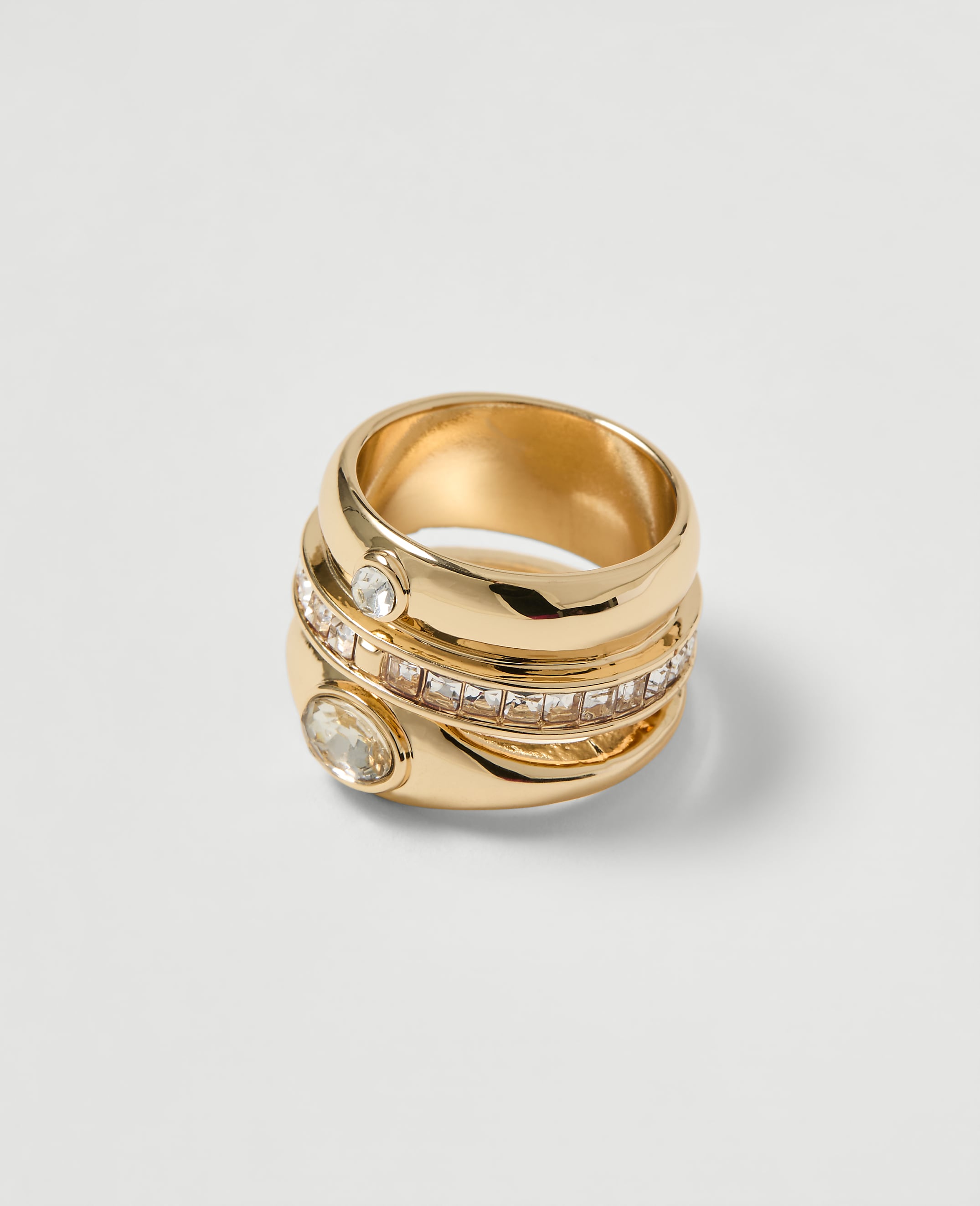 A gold ring with clear stones is displayed against a plain white background.