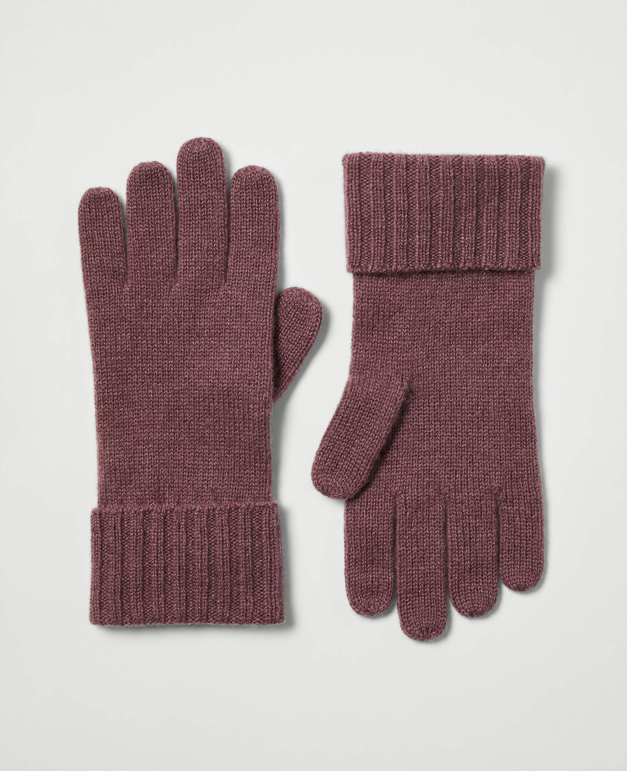 A pair of rose-colored knit gloves with ribbed cuffs rests on a plain, light gray background.