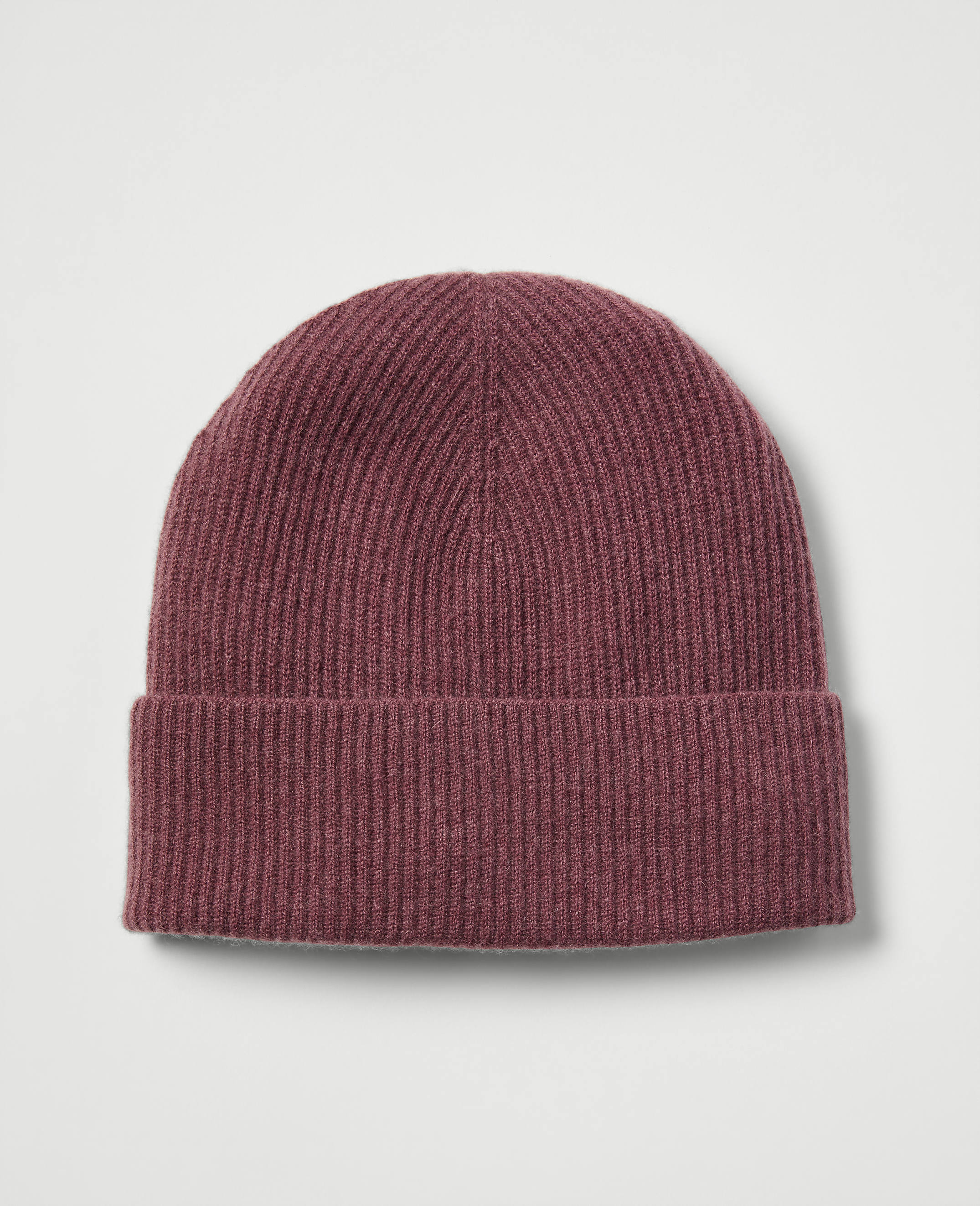 A maroon ribbed beanie with a folded brim rests against a plain, light gray background.