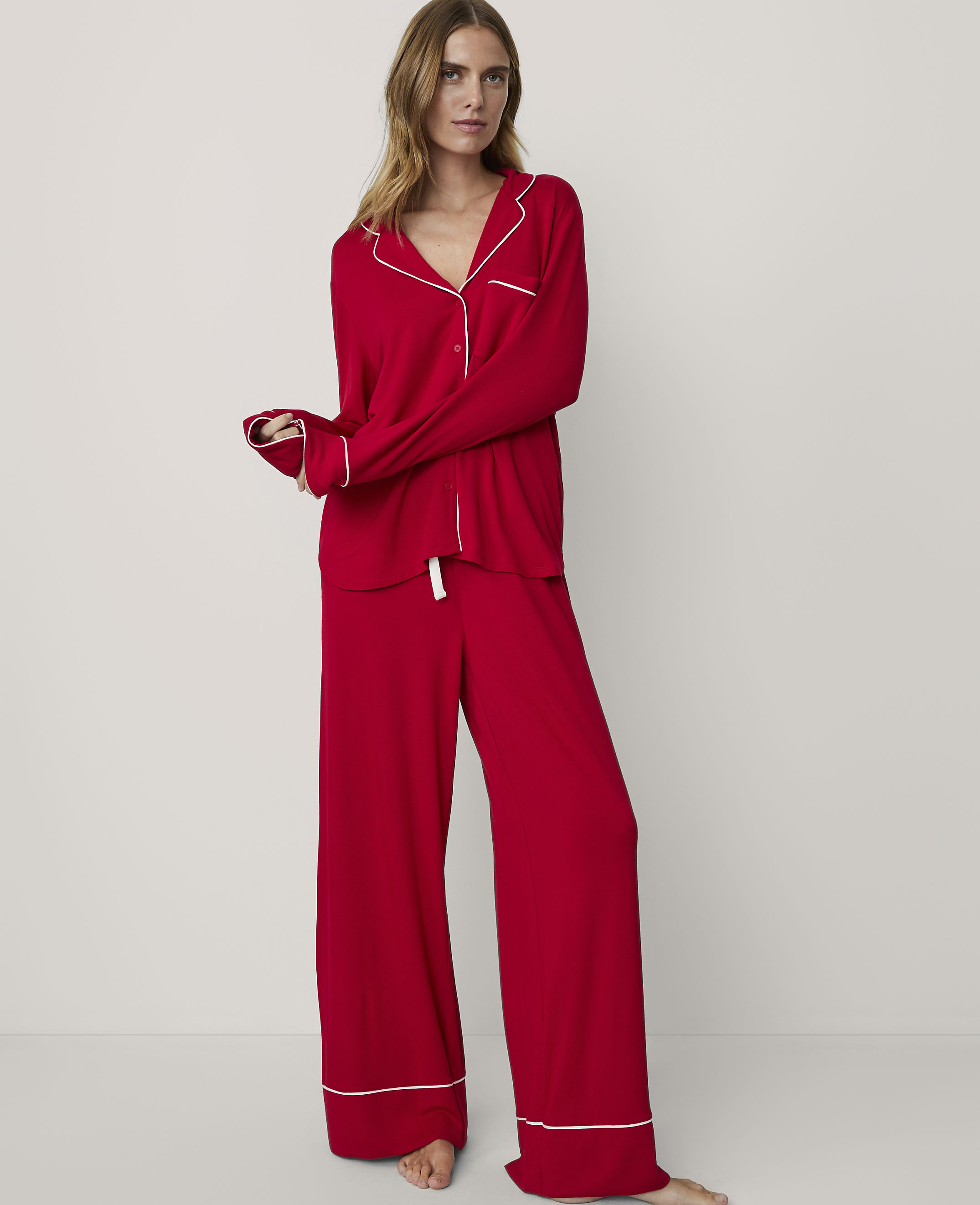 A woman in red pajamas stands against a plain white background.