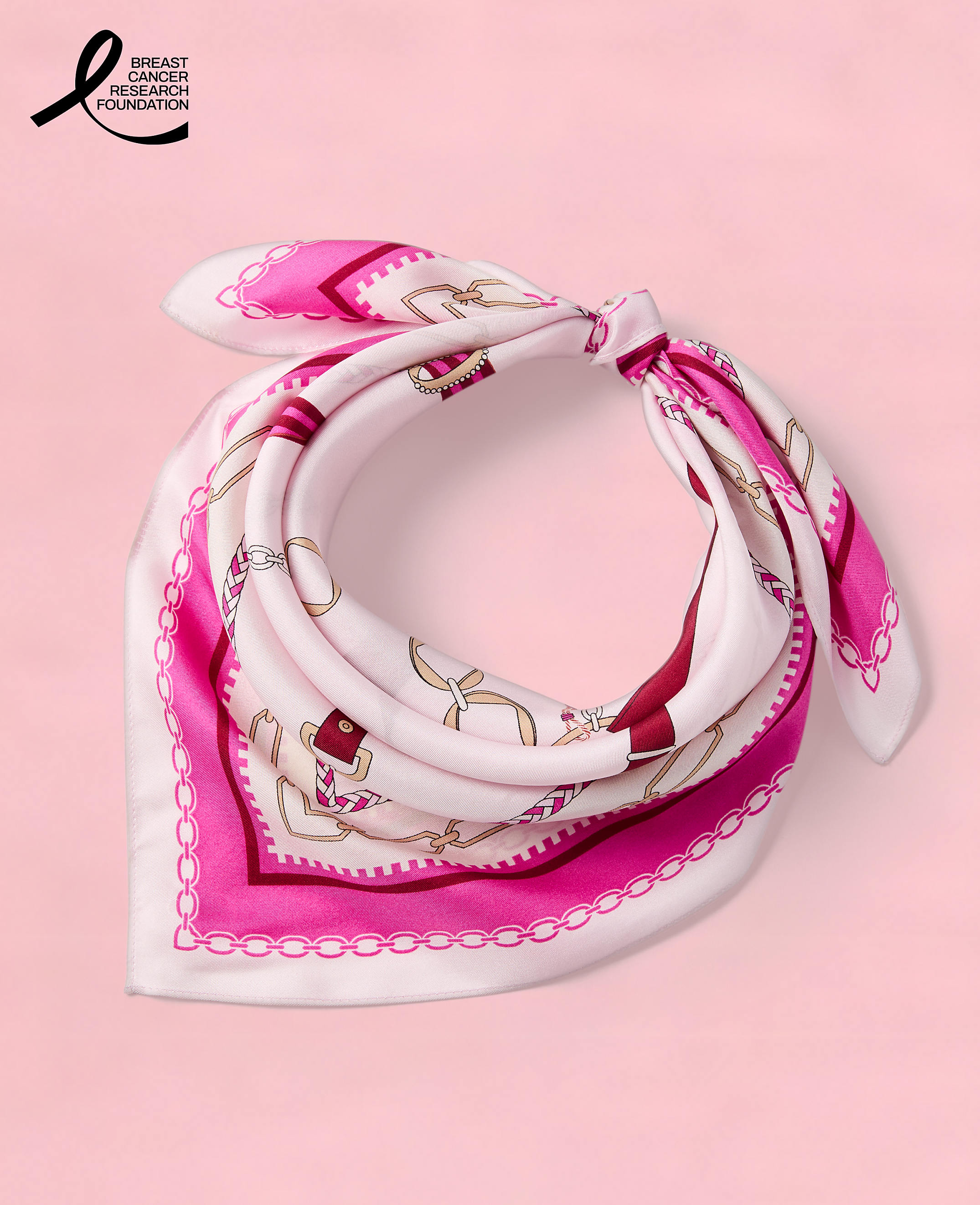 A pink silk scarf with a chain and anchor pattern is tied in a knot against a white background.