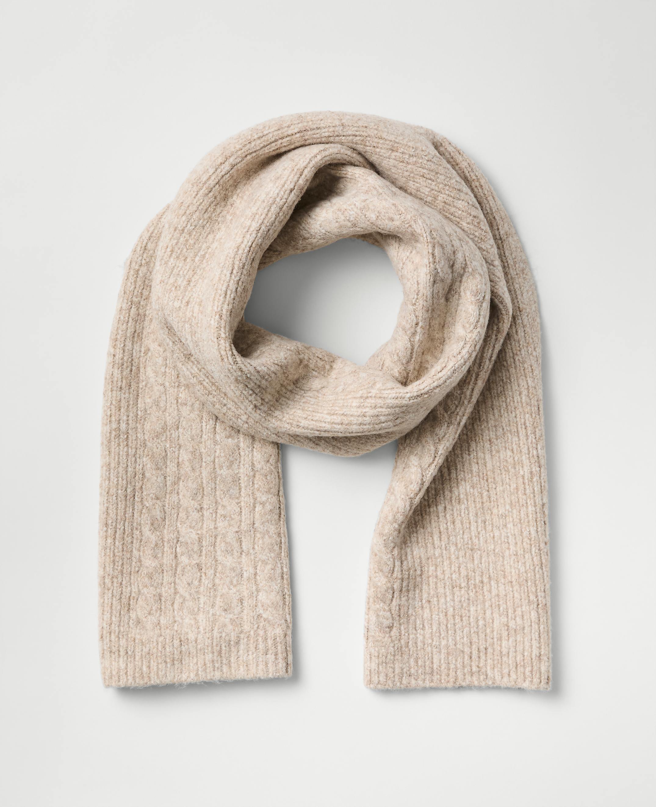 A beige ribbed knit scarf is draped in a loop against a plain light gray background.