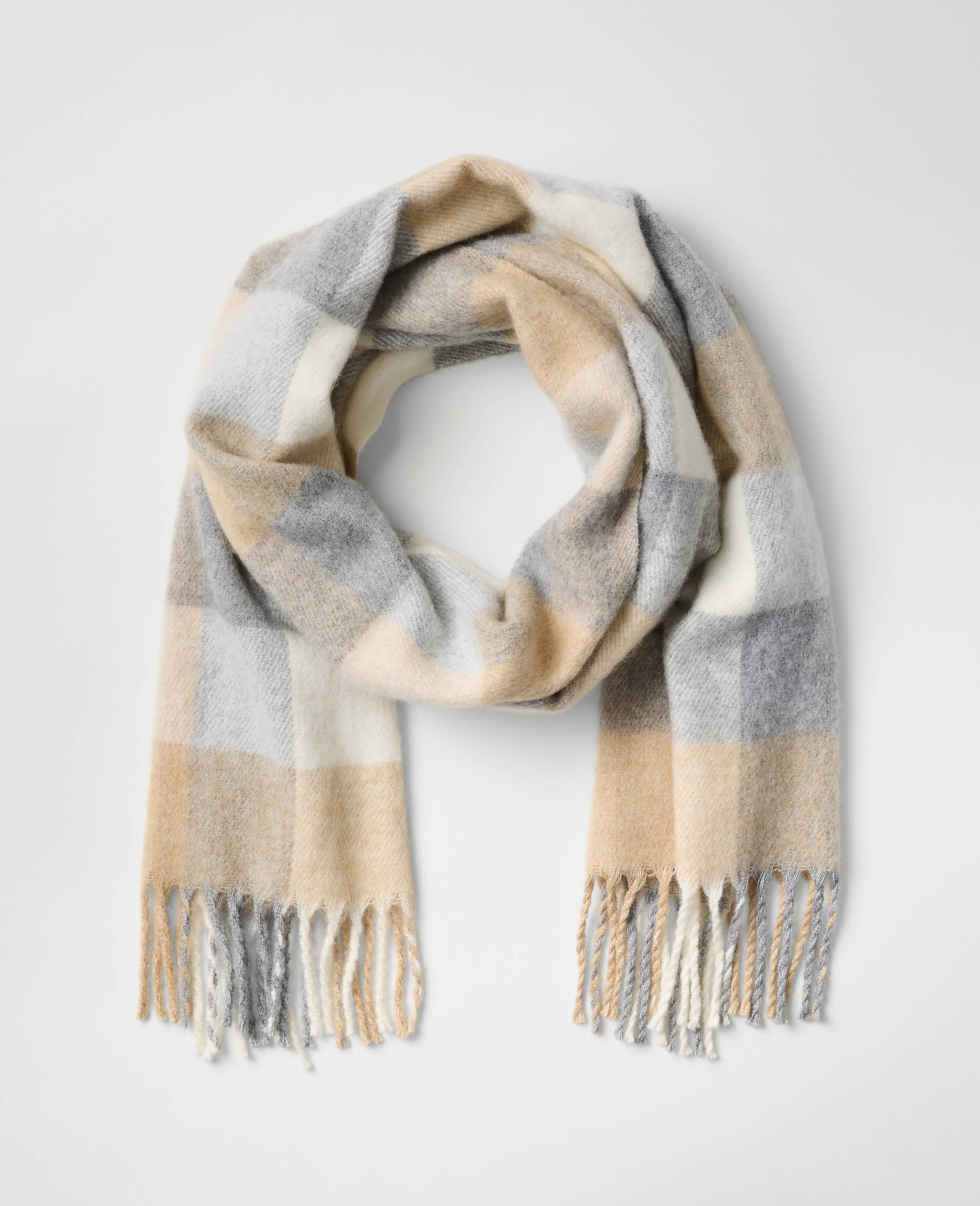 A beige, grey, and white plaid scarf with fringed ends is laid out against a plain light grey background.