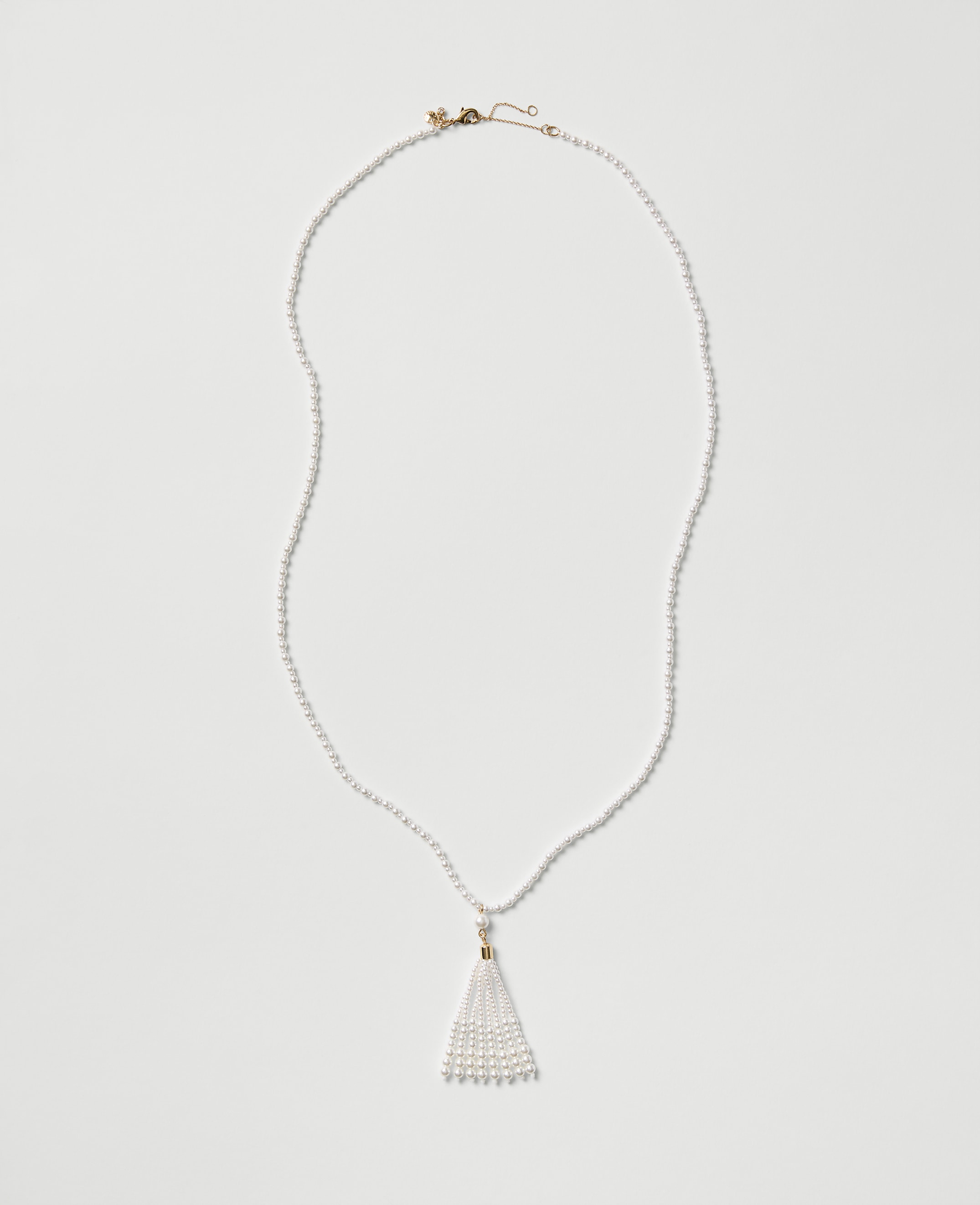 A white pearl necklace with a tassel pendant rests on a plain light gray background.