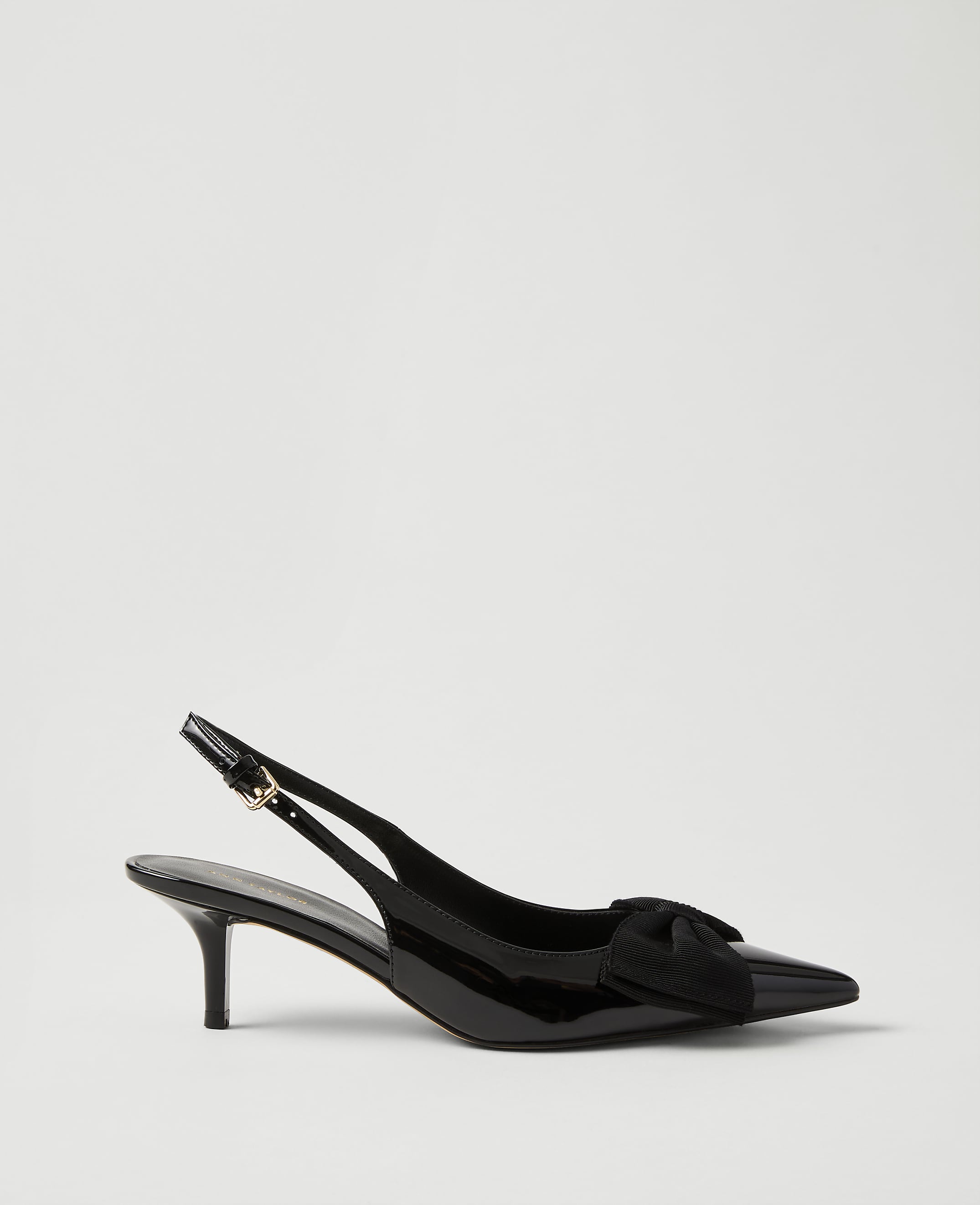 A single black patent leather slingback heel with a bow detail sits against a plain, light gray background.