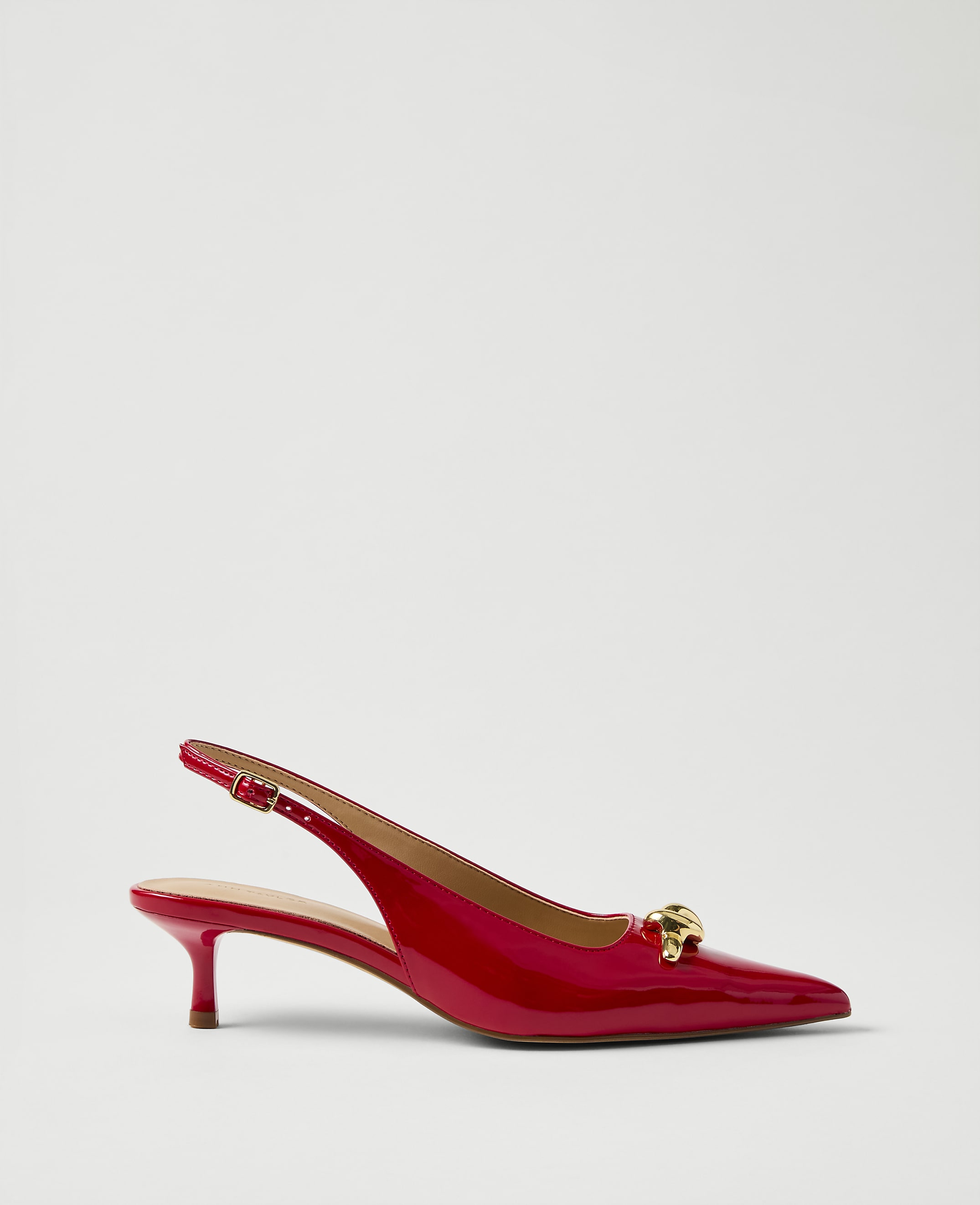 A red patent leather slingback heel with a gold ornament sits against a plain white background.