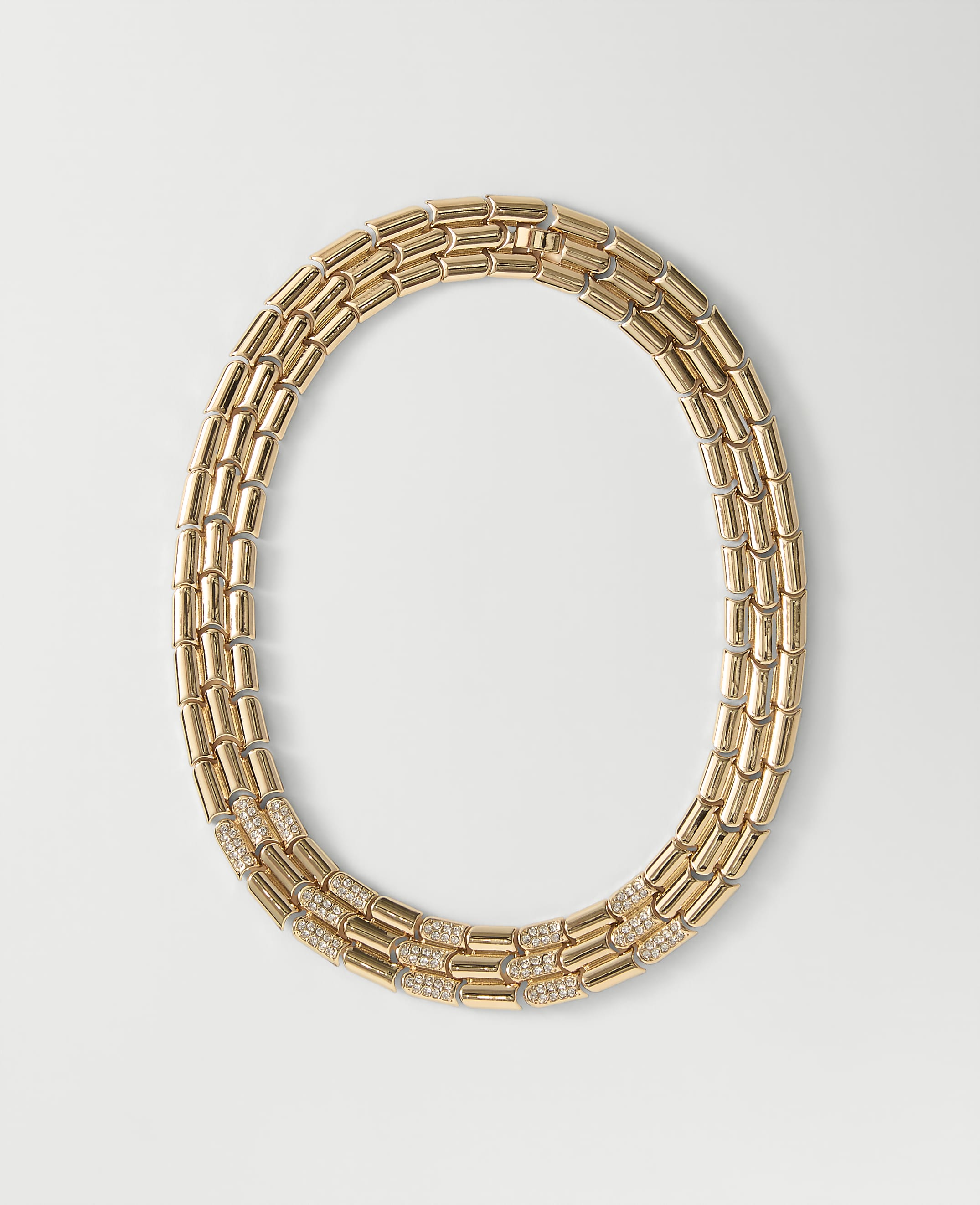 A gold link necklace with diamond accents rests on a plain white background.