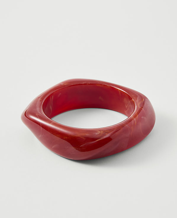 A red, swirled resin bangle rests on a plain white background.