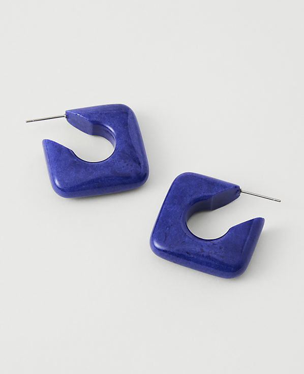 A pair of square, royal blue hoop earrings with a marbled texture rest on a plain white background.