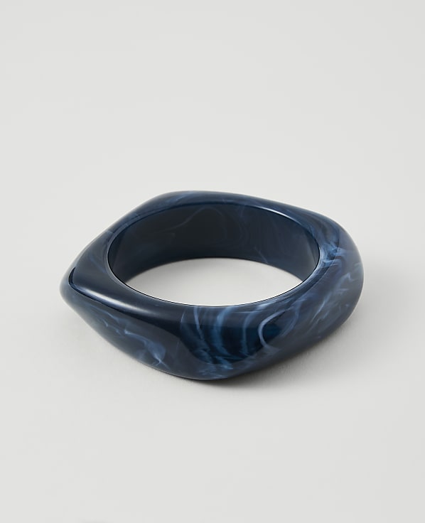A dark blue, marbled bangle rests on a plain white background.