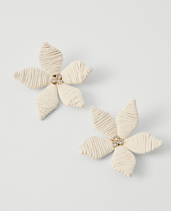 Two cream-colored floral earrings with rhinestone centers rest on a plain white background.