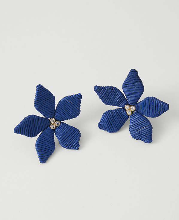 Two blue floral earrings with jeweled centers rest on a plain white background.