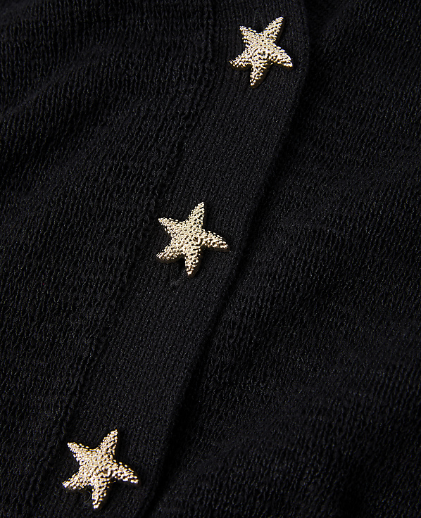 Three golden starfish buttons are sewn onto a textured black fabric.