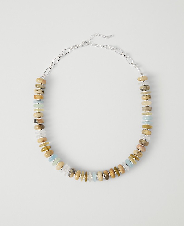 A colorful beaded necklace with a silver chain rests on a plain white background.