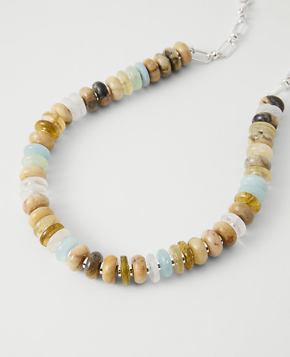A colorful beaded necklace with various stones rests on a plain white background.
