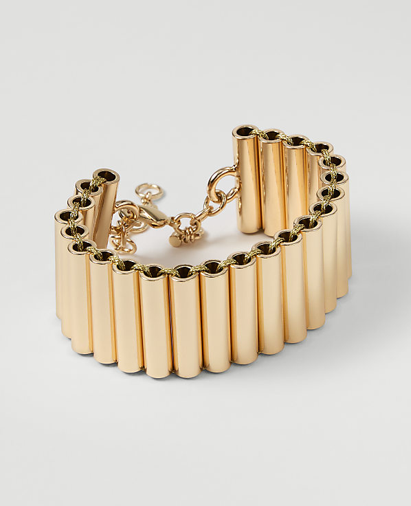 A gold cuff bracelet with a series of vertical tubes is displayed against a plain white background.