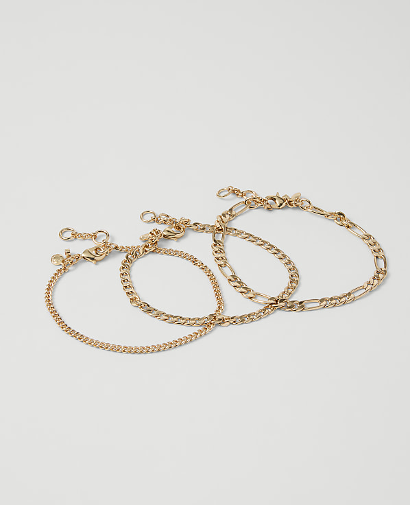 Three delicate gold chain bracelets are arranged on a plain white background.