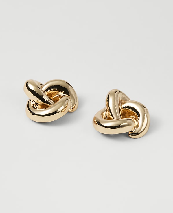 Two gold knot-shaped earrings rest on a plain white background.