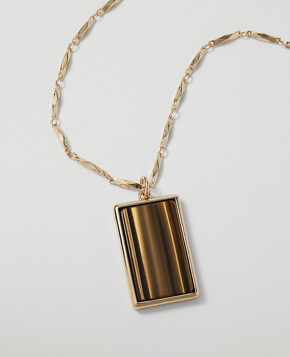 A rectangular tiger's eye pendant hangs from a delicate gold chain against a plain white background.