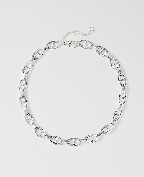 A silver chain necklace with oval links lies on a plain white background.
