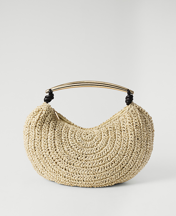 A beige crocheted crescent-shaped handbag with a gold curved handle rests against a plain white background.