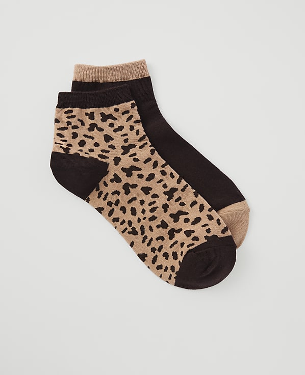 A pair of ankle socks, one with a leopard print and the other solid brown, rest on a plain white background.