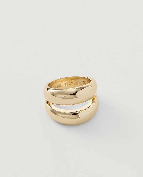 Two stacked gold rings with "ANN TAYLOR" inscribed on the inner surface rest on a plain white background.