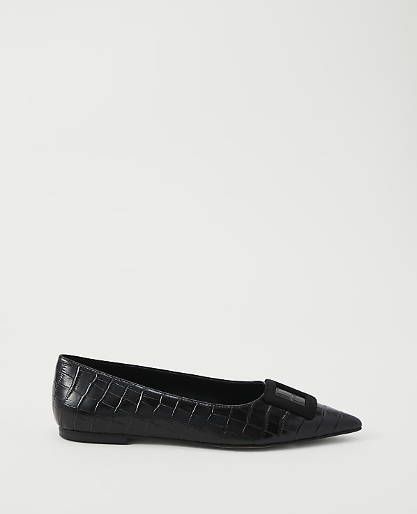 A black, pointed-toe ballet flat with a textured finish and a decorative buckle sits on a plain white background.
