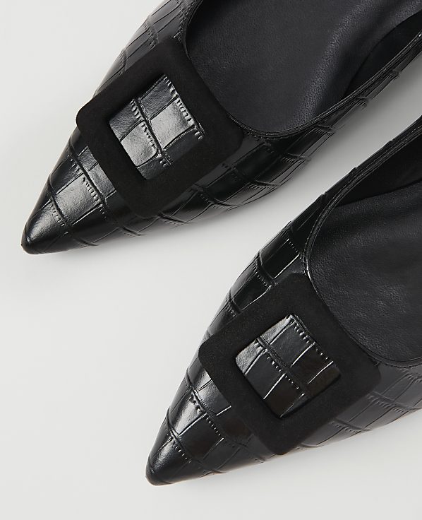 Two black, pointed-toe heels with croc-embossed texture and a square black buckle are laid out on a white background.